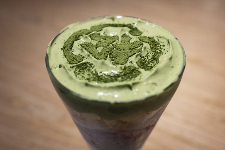 Overhead view of a green cream-topped matcha parfait in a sundae glass.