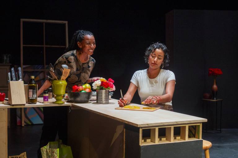 Two women talk at a long table with settings