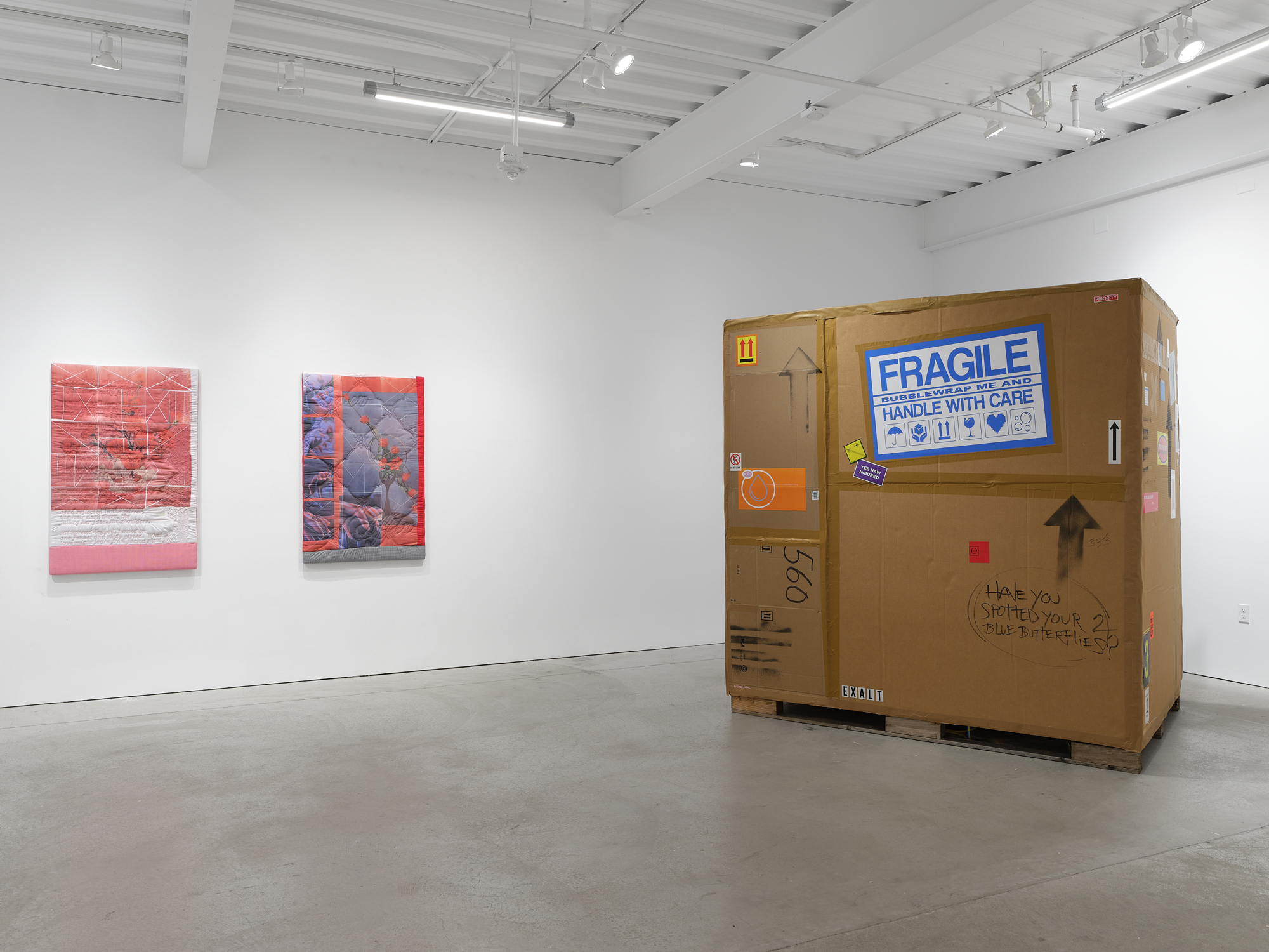 gallery view with textile work and overly large carboard box