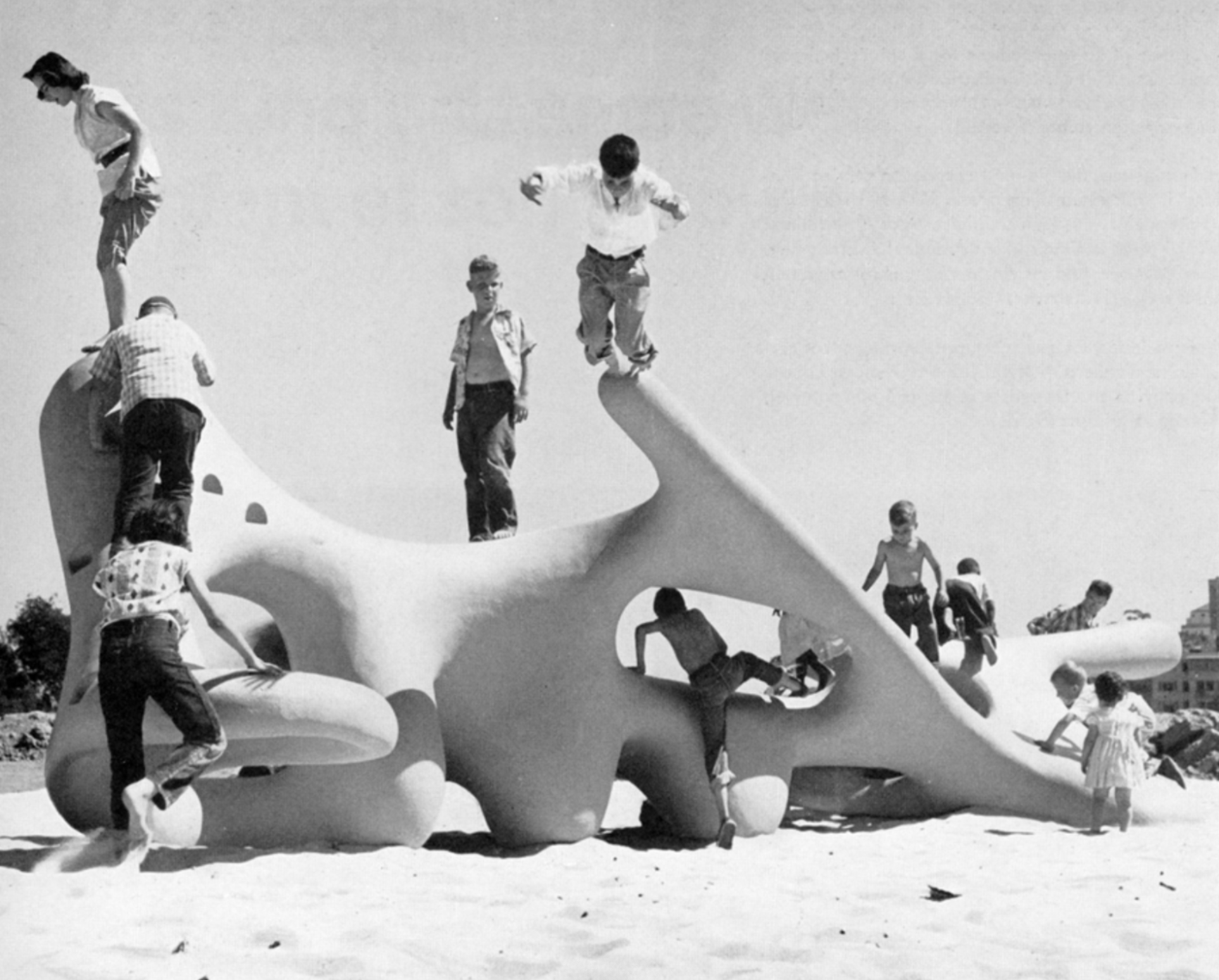 black and white photo of children playing on soft curved gloopy shaped sculpture