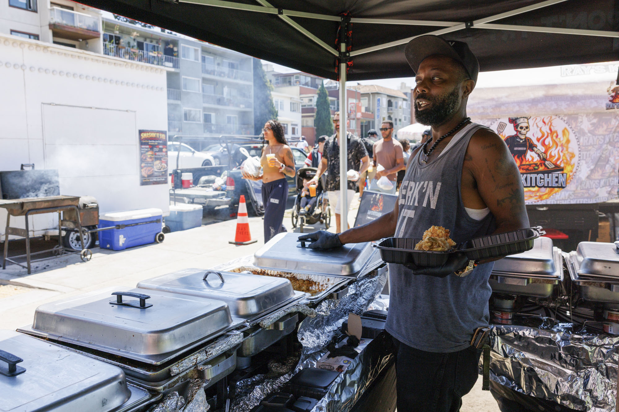 A chef in an outdoor food tent plates up a dish of food.