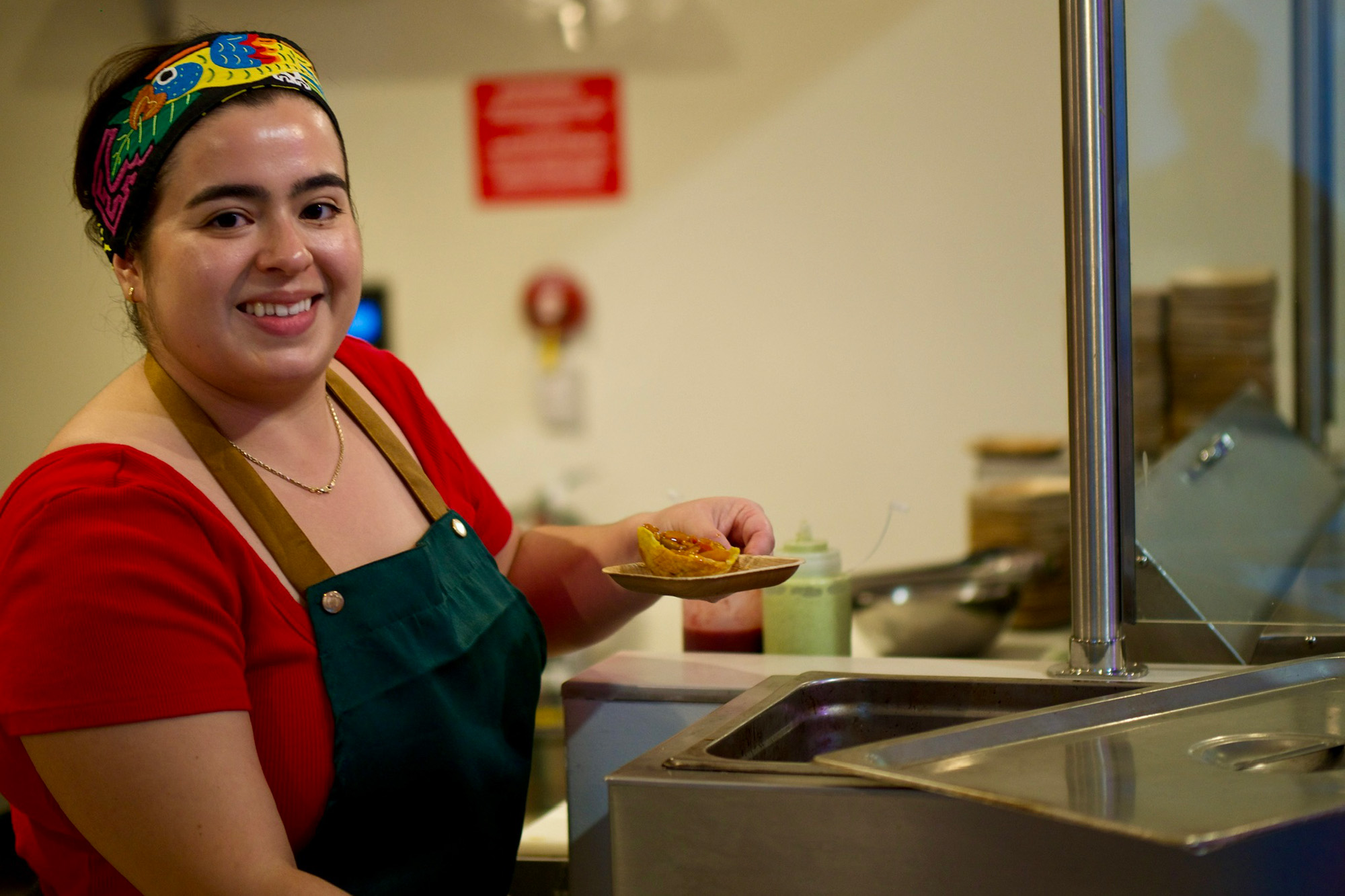 A smiling chef preps food inside a commercial kitchen.