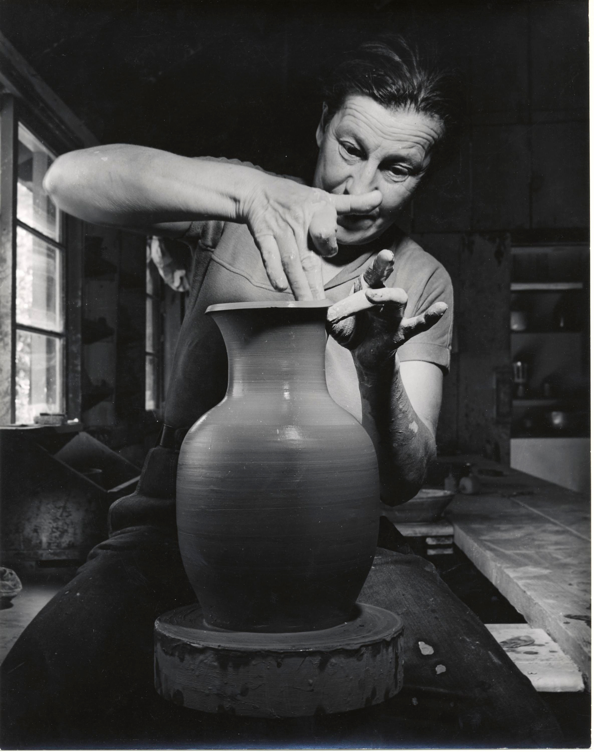black and white photo of woman shaping a ceramic vase on a wheel