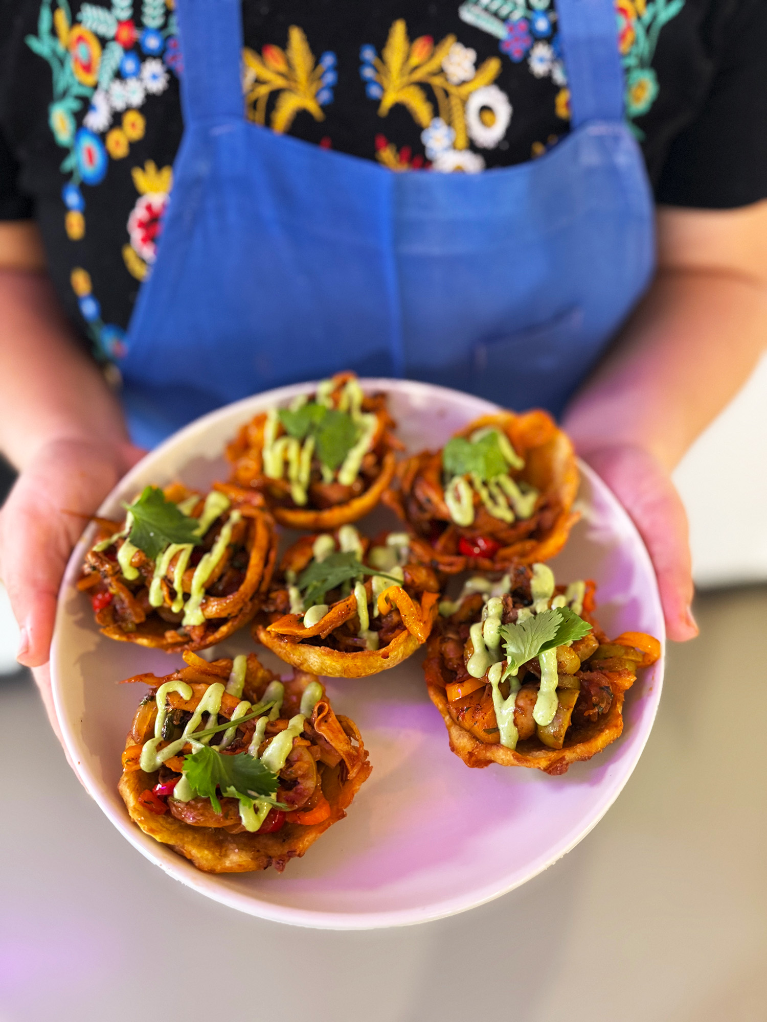 Hands holding a plate of loaded Panamanian patacones (fried green plantains).