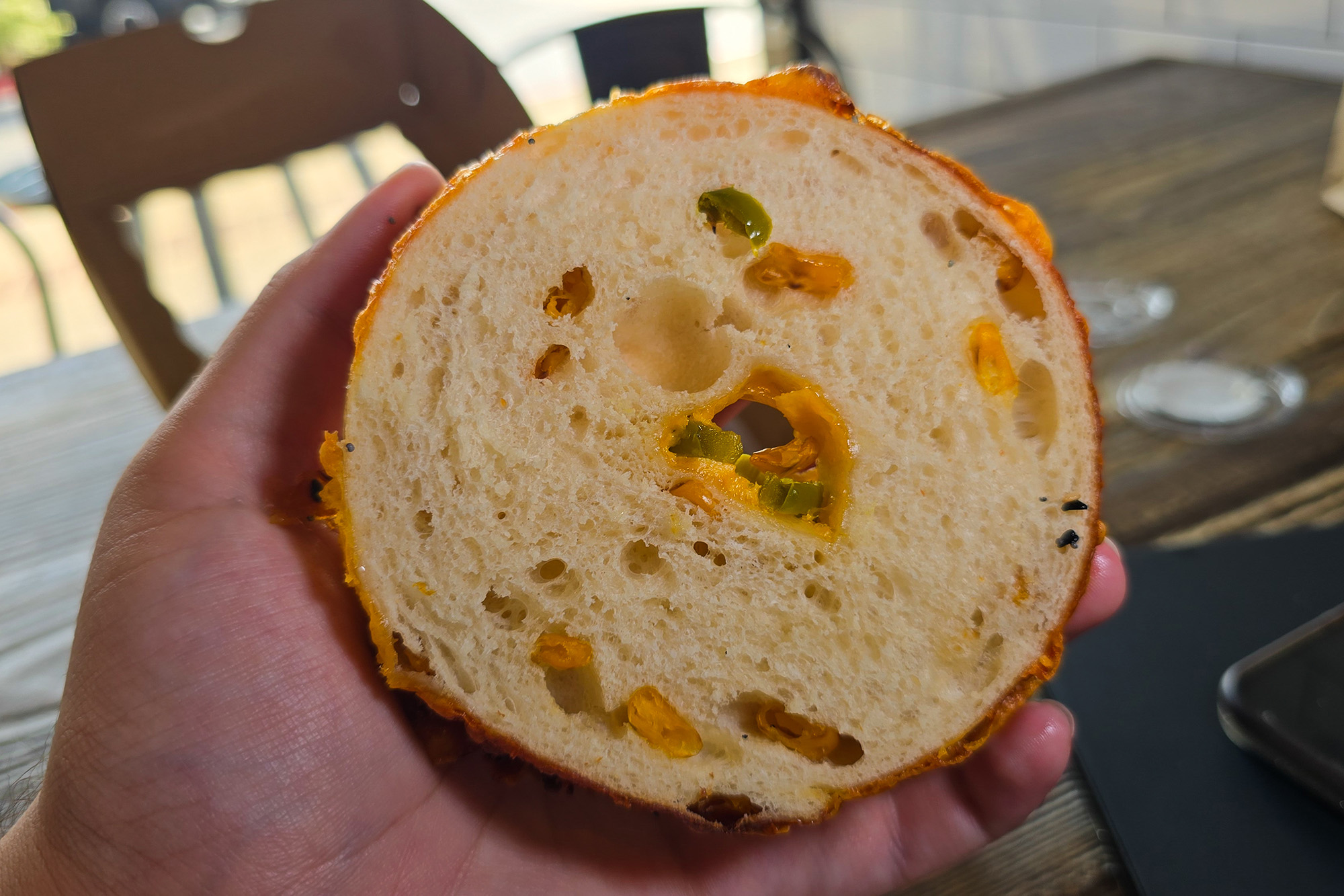 Cross section of a bagel, with bits of corn, jalapeño and cheddar cheese visible.