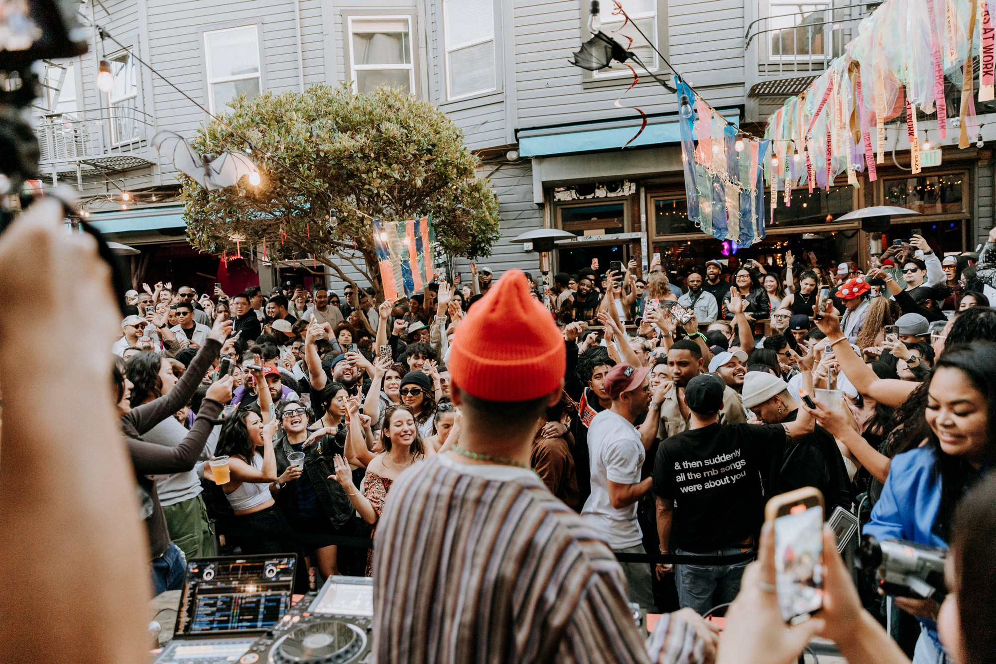 large crowd in bar backyard, DJ facing them
