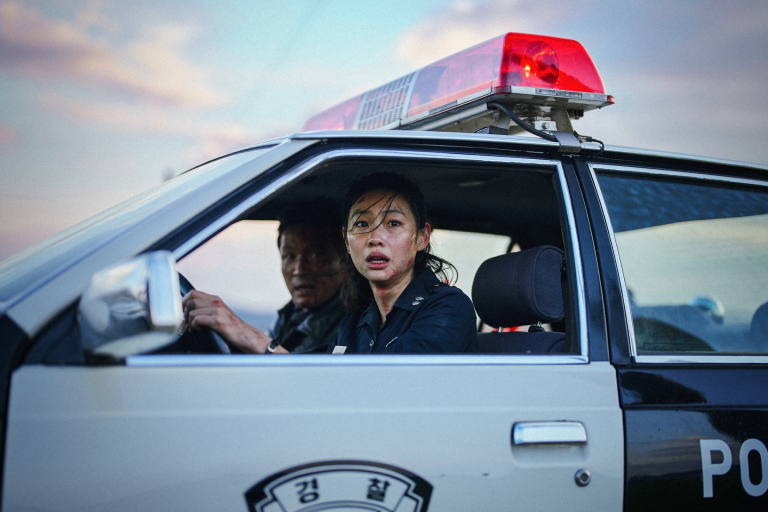 a man and a woman look distressed driving a police car
