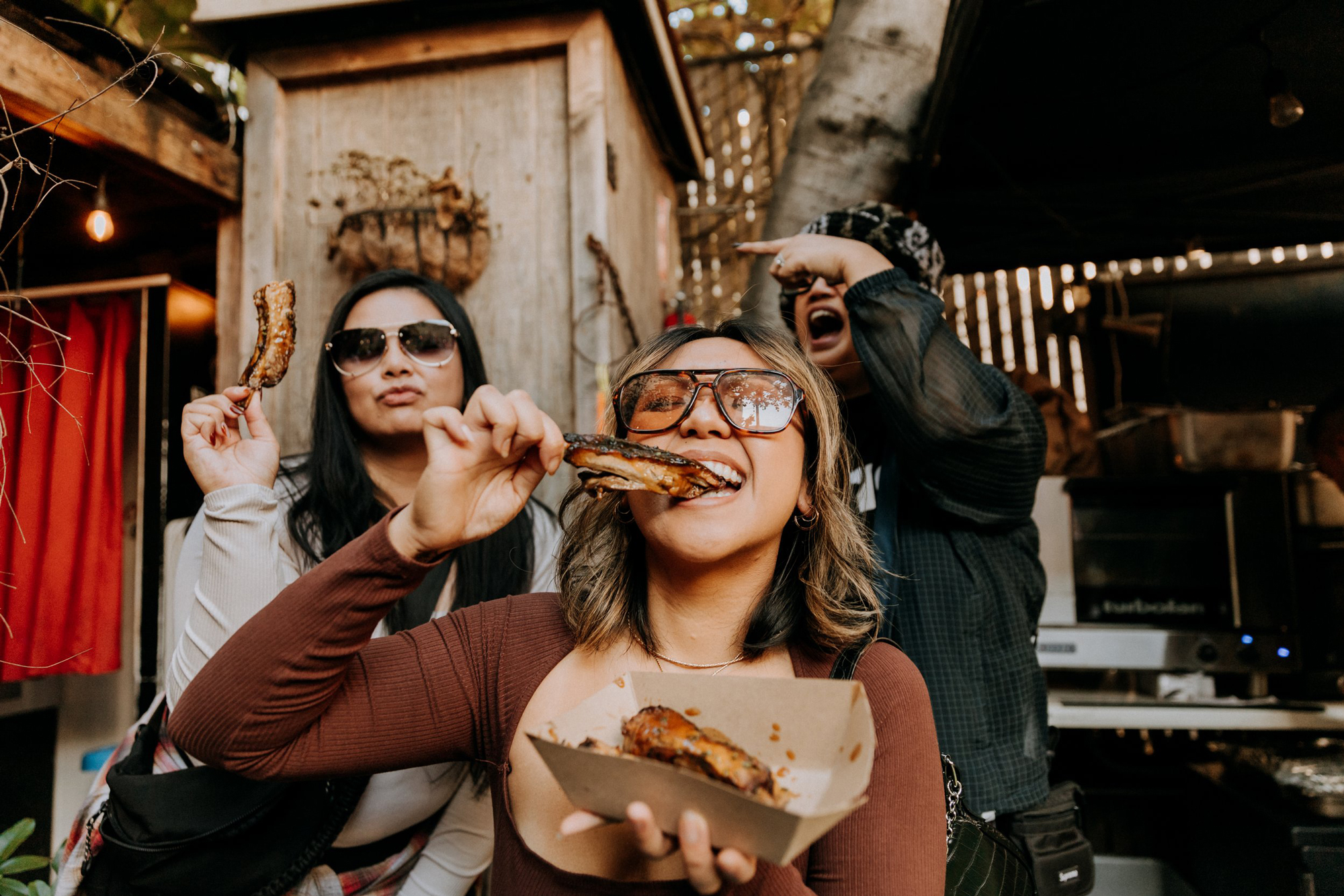three women cheer and eat ribs