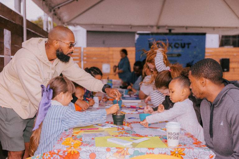 Parents and small children sit around a table and work on crafts.