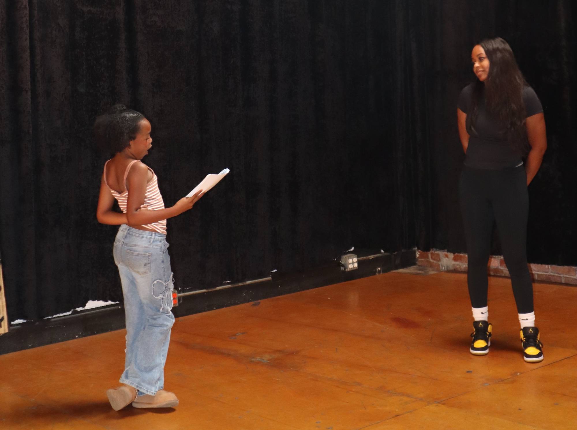 A girl and a woman in a studio, rehearing for a play.