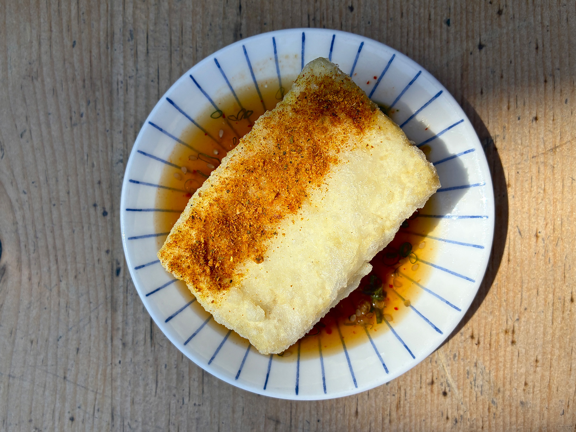 Large block of fried tofu, the top half of which is dusted with spice.