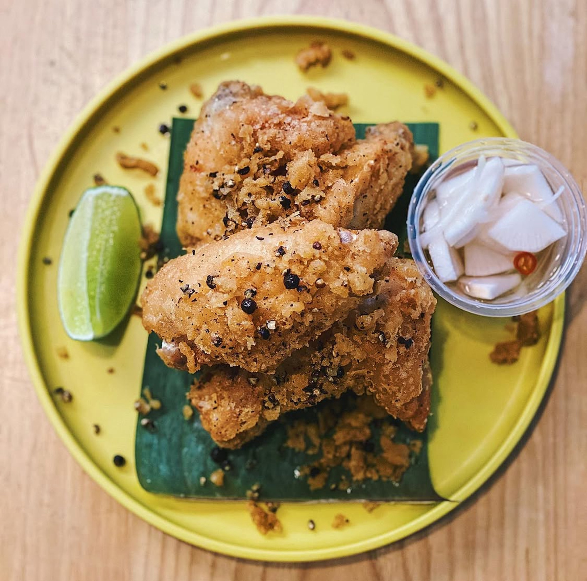 Fried chicken wings topped the black peppercorns, with pickled radishes and a lime wedge on the side.