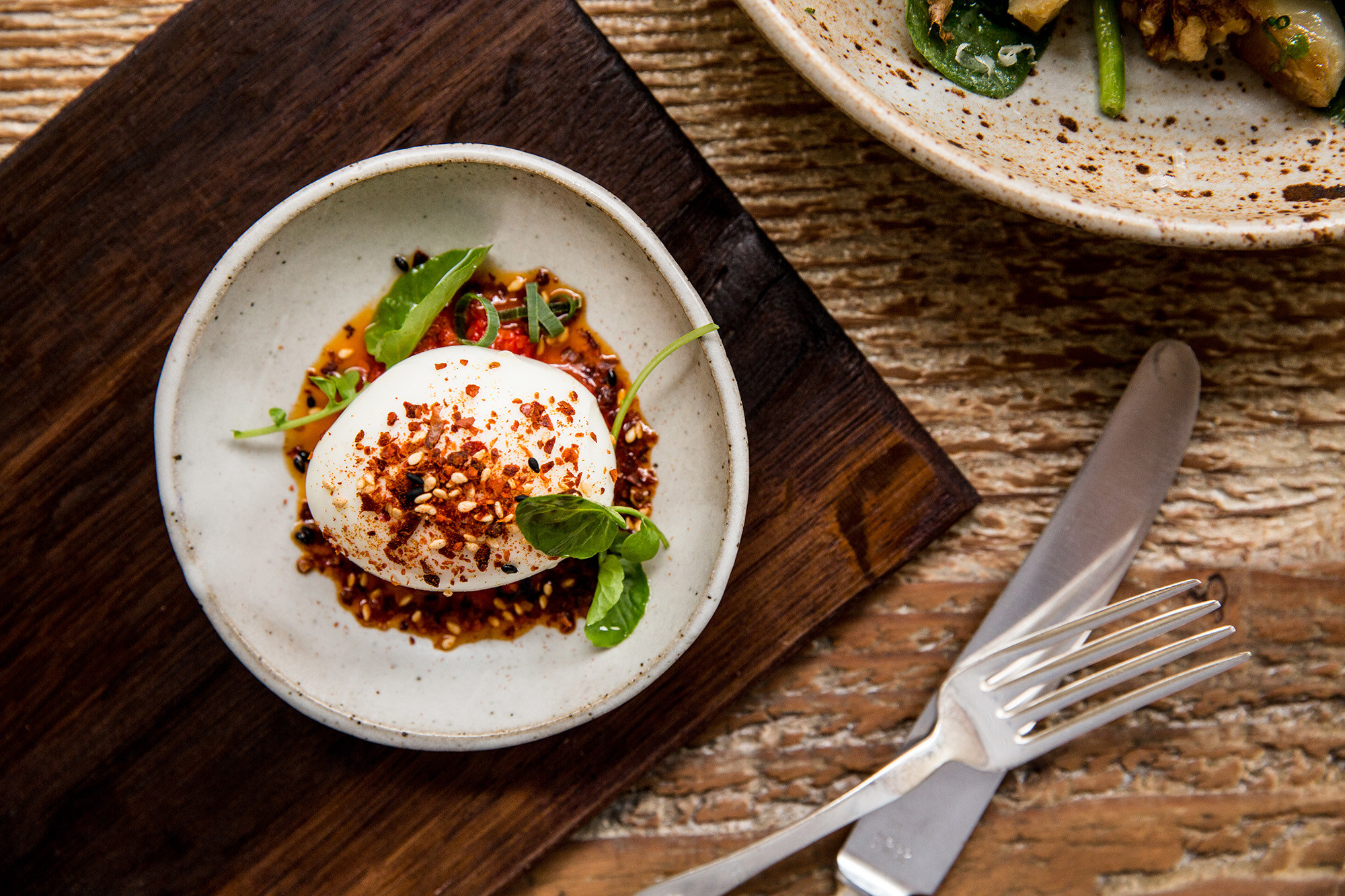A soft-boiled egg topped with dried chilies and sesame seeds.