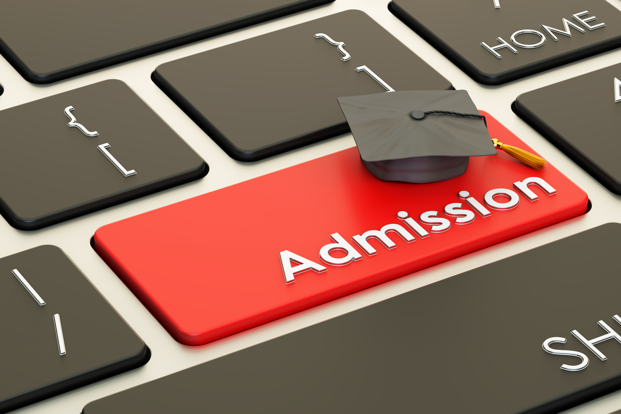 Closeup of several keys on a computer keyboard. Mostly black keys with center key in red and the word "Admission" insteadof a letter of symbol. A small graduation cap rests on the key.