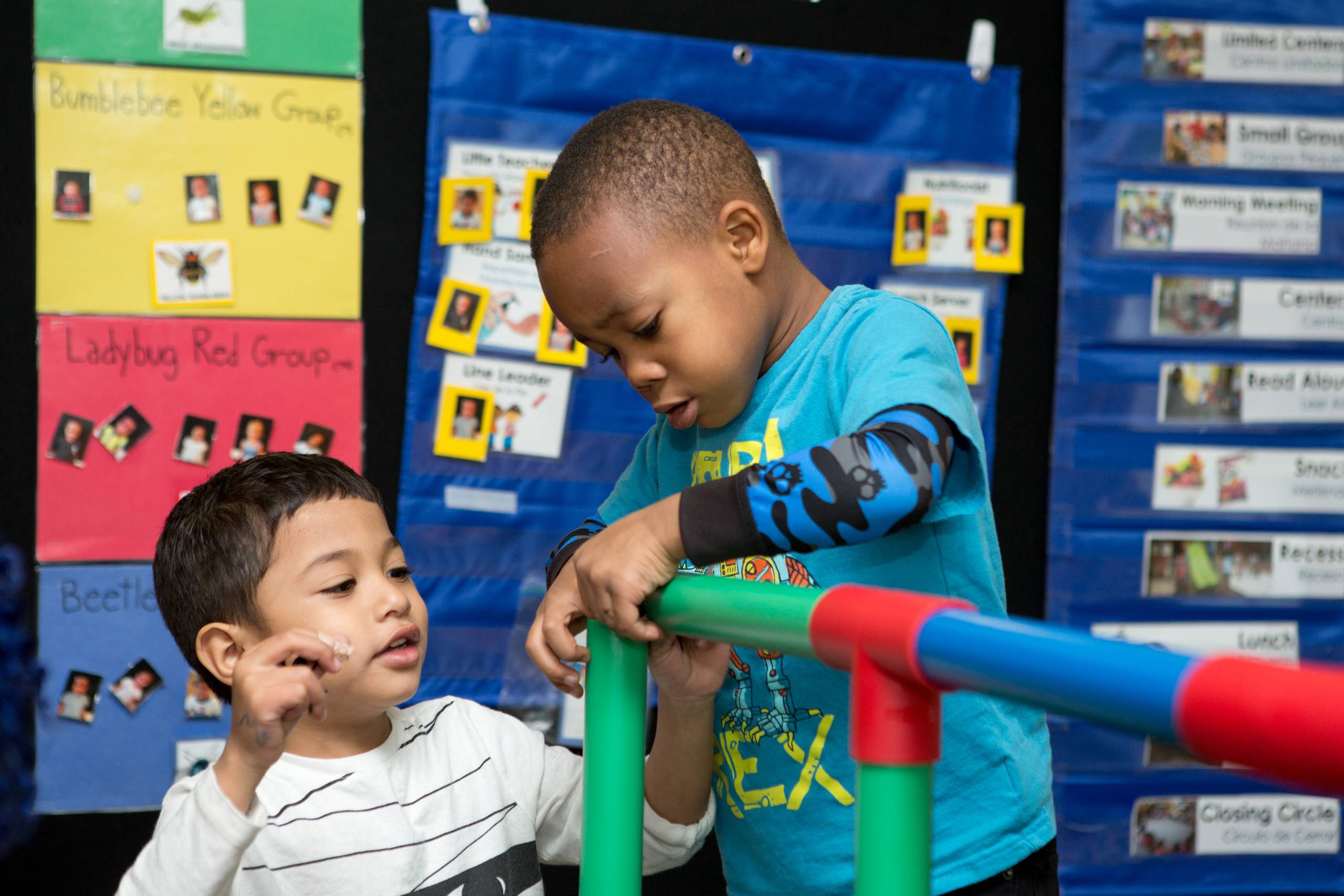 Preschool students build a structure from plastic interlocking tubes.