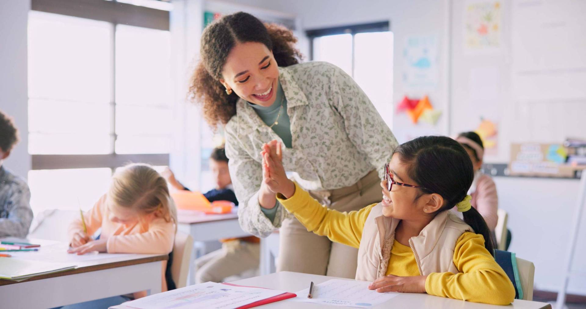 Teacher and student high five in a classroom.