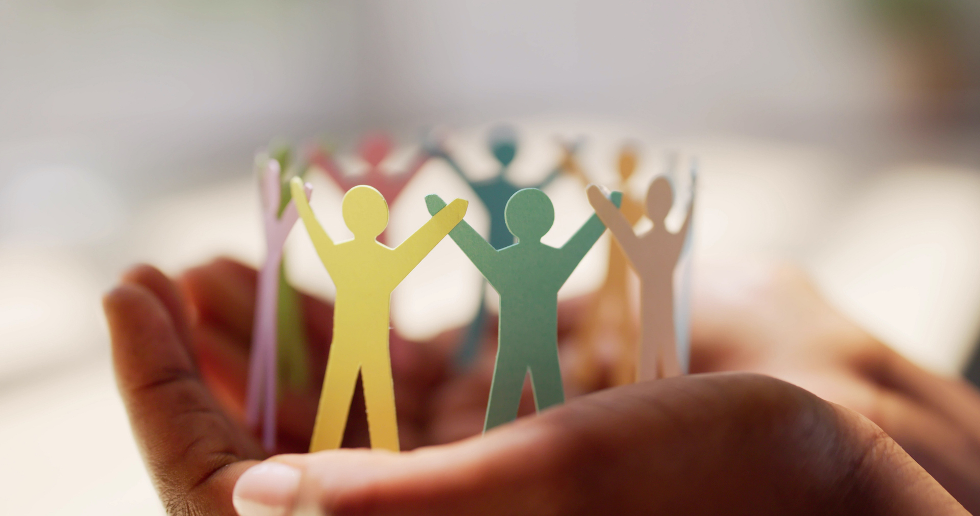 paper cutouts of people held in two hands