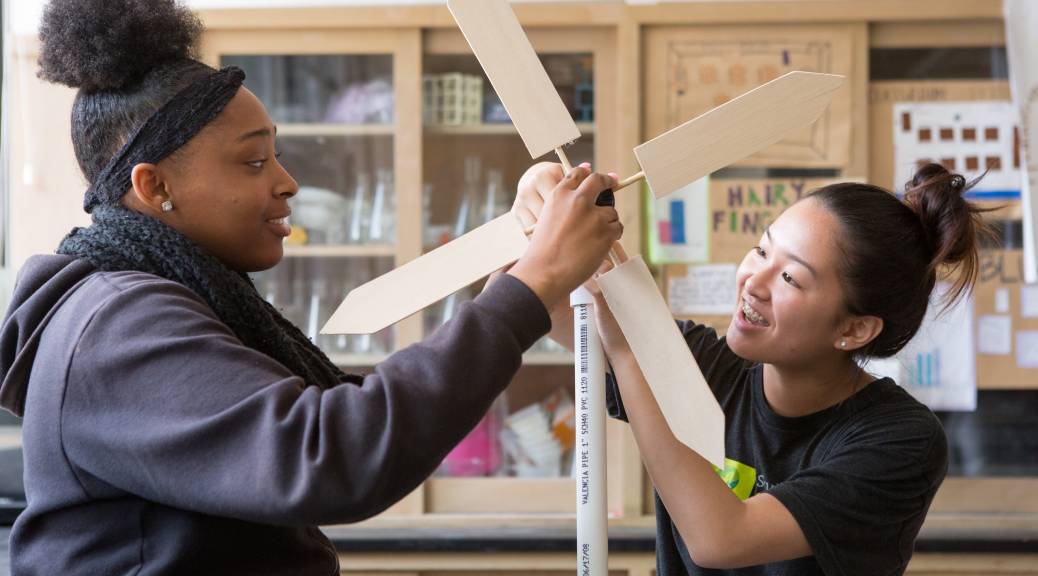 Two students with hands on a turbine