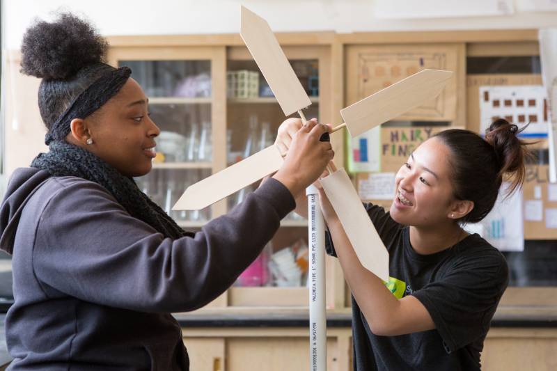 Two students with hands on a turbine