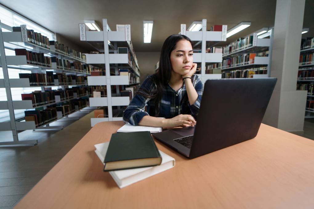 Female student using laptop at table in library