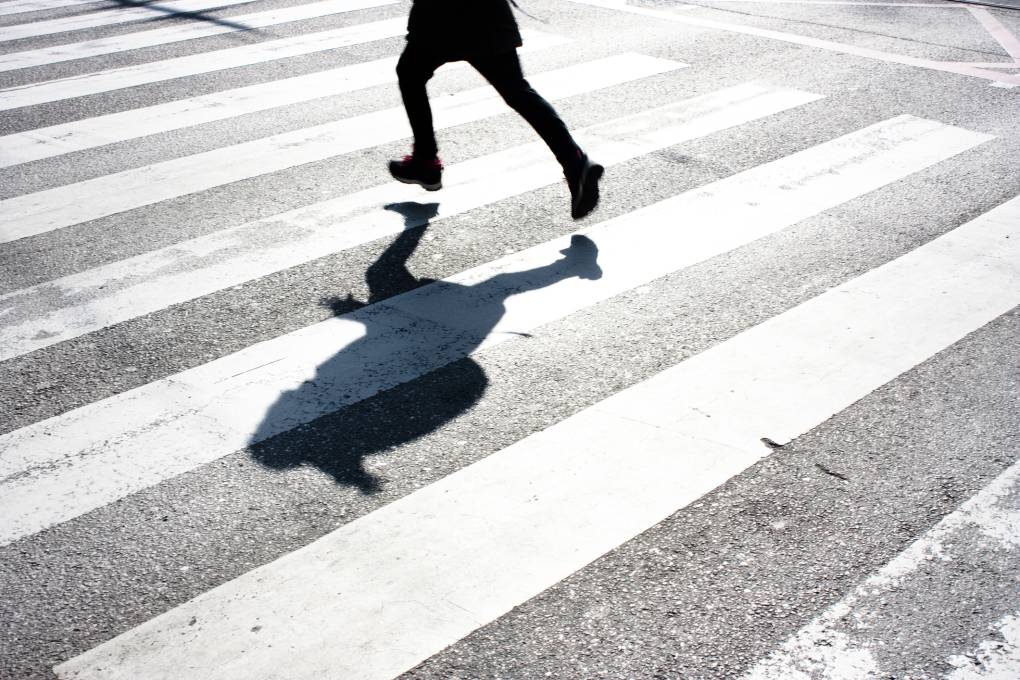 Shadow of a child with backpack crossing the street