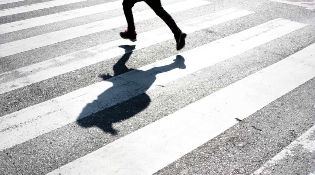 Shadow of a child with backpack crossing the street
