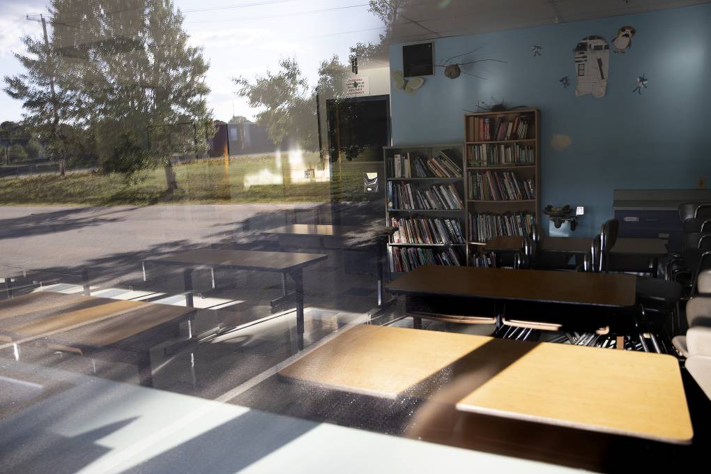 Empty desks seen through a window of a classroom