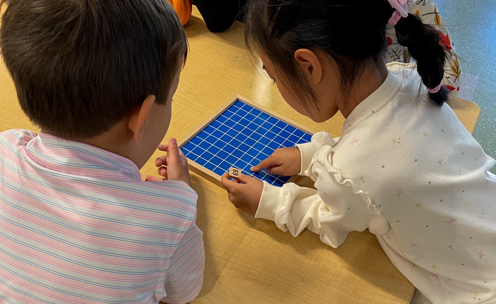 Two children place numbers on a grid