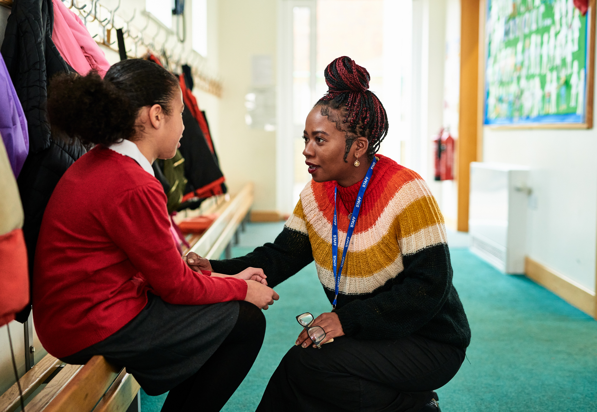 Elementary school girl sitting on bench talking to teacher