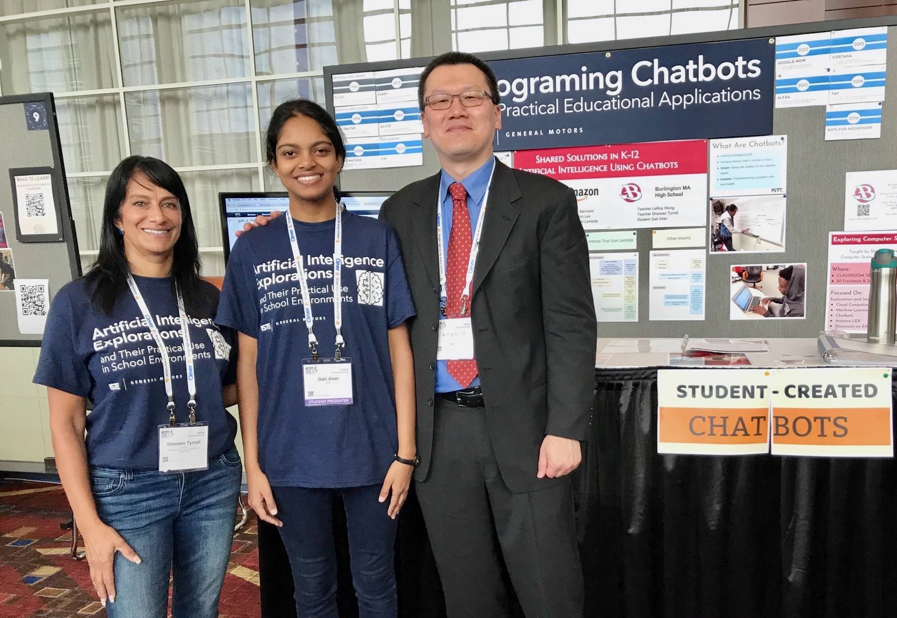 Three people stand in front of display about chatbots