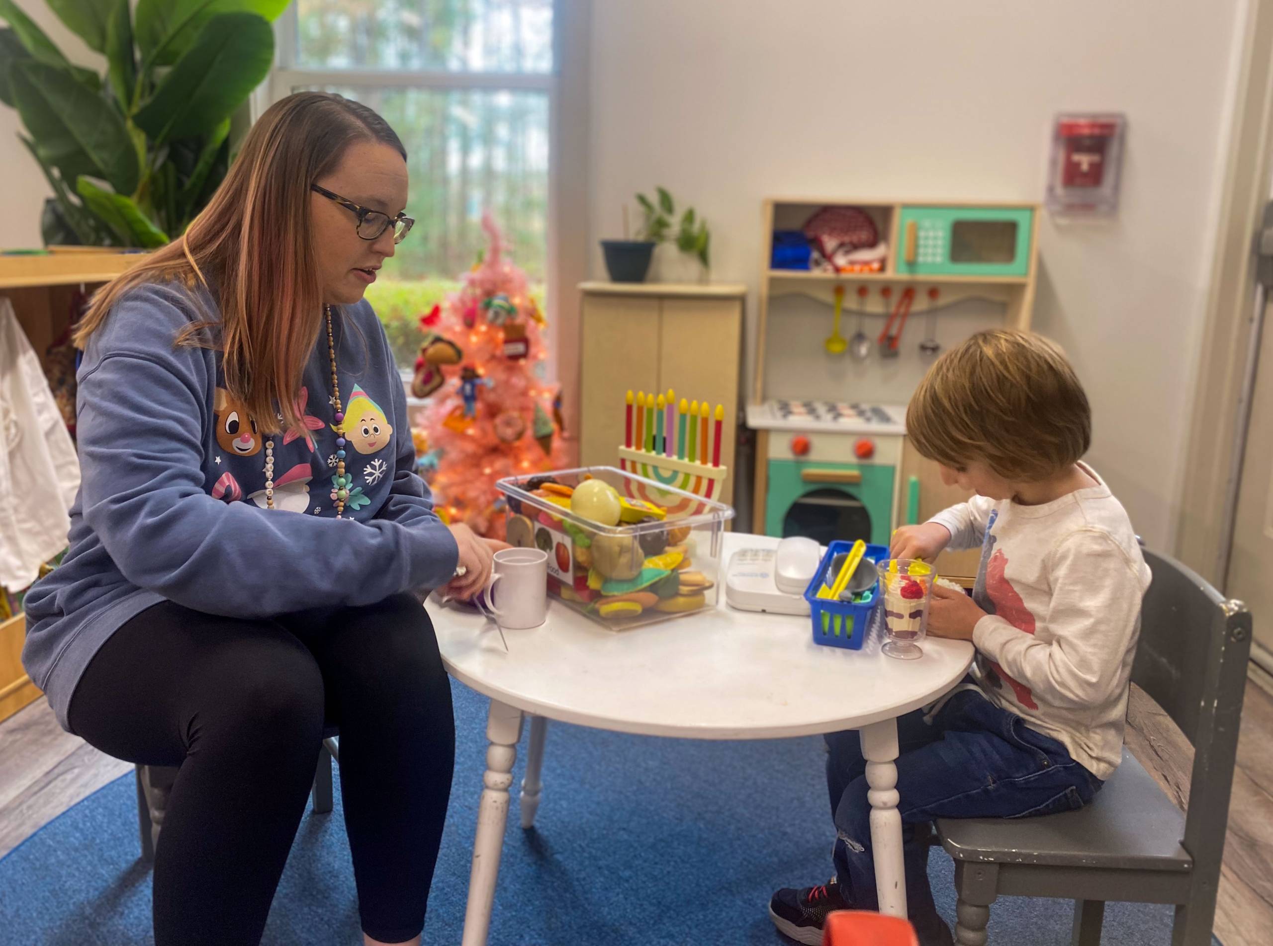 Teacher and child sitting at a table in a classroom