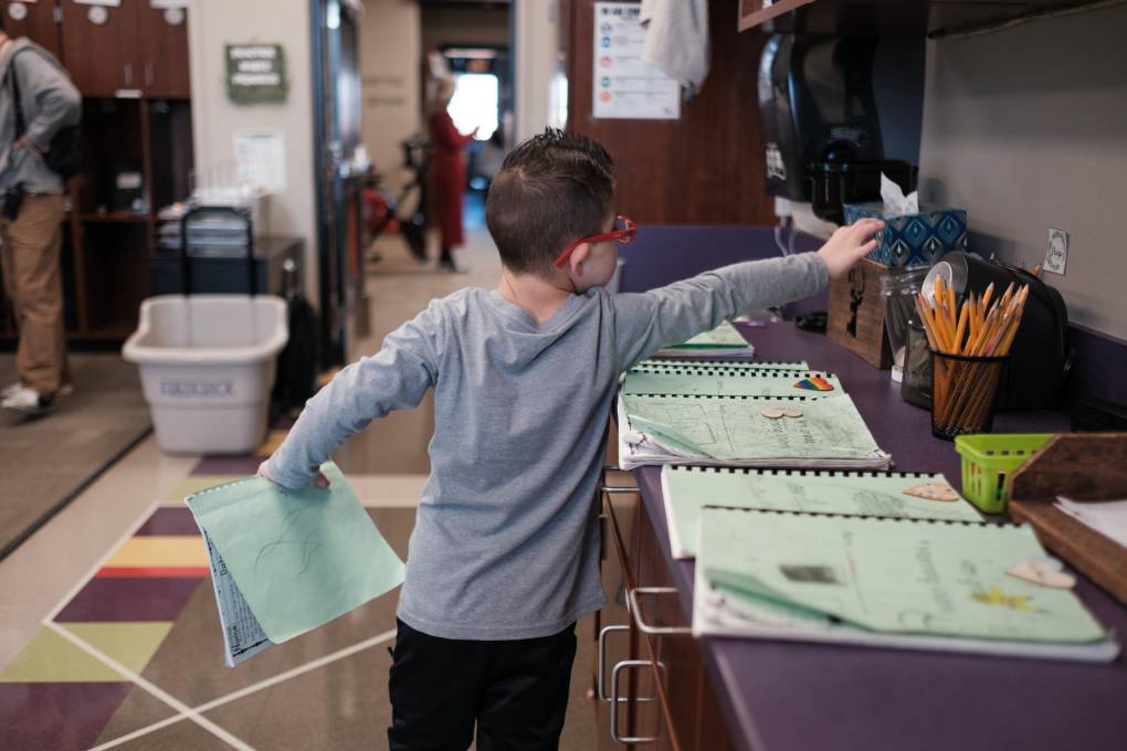 A student reaches for supplies in a classroom