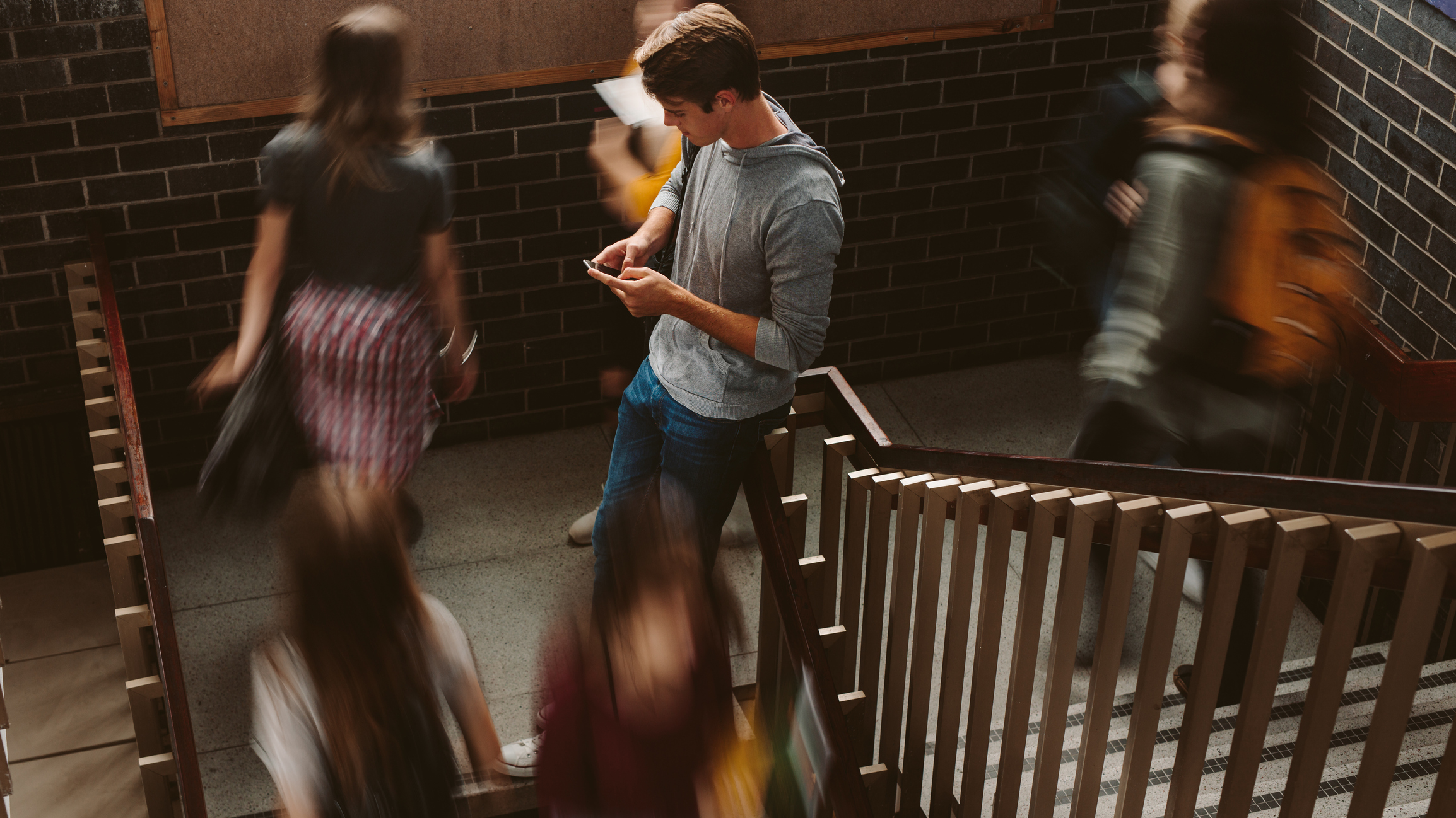 Young man on phone while crowd passes by