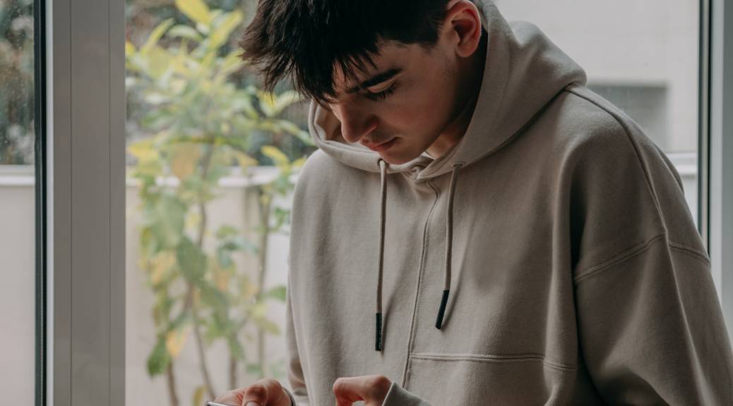 Teenage boy at home looking at mobile phone.