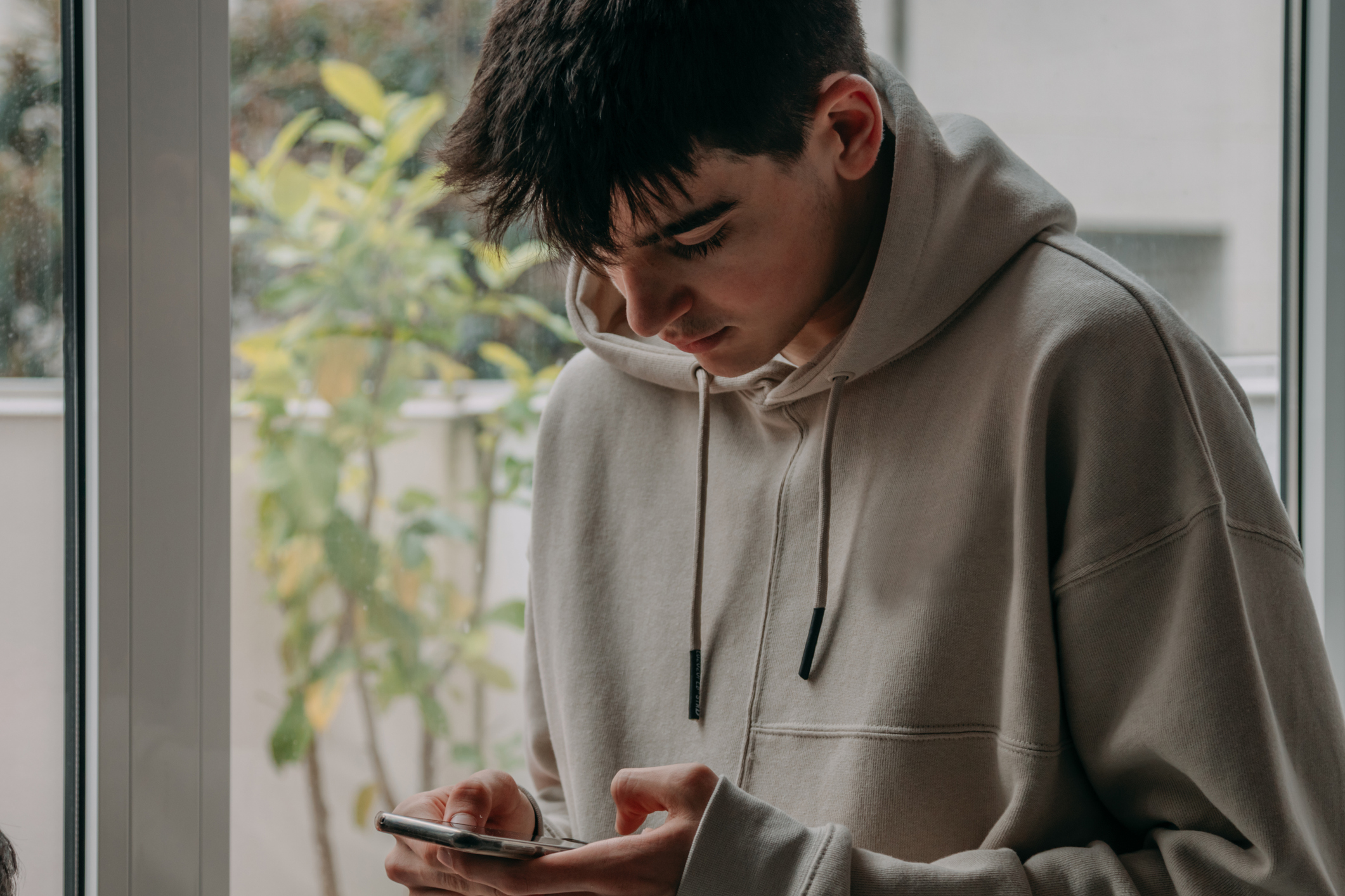 Teenage boy at home looking at mobile phone.
