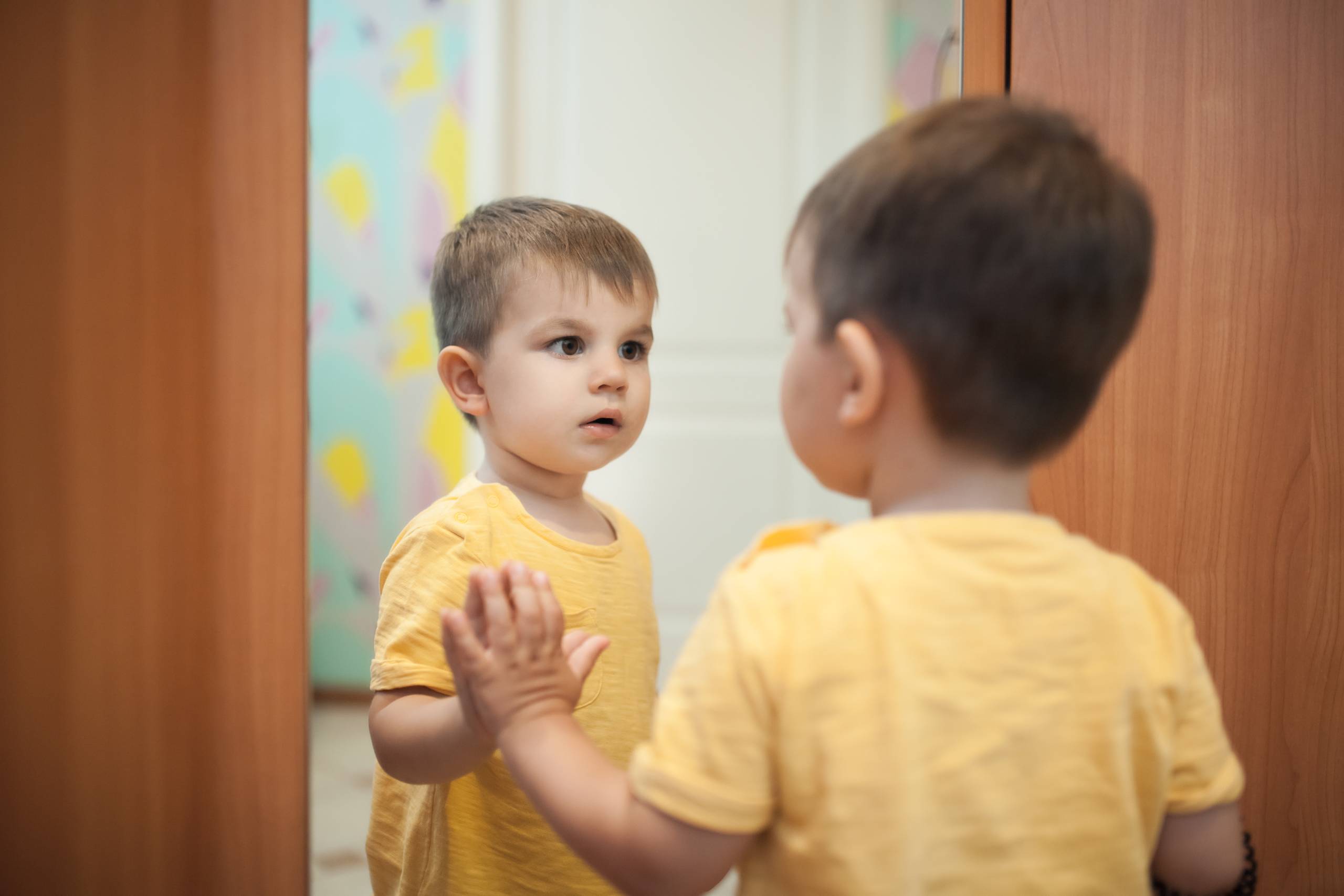 Young child looking at his reflection in the mirror