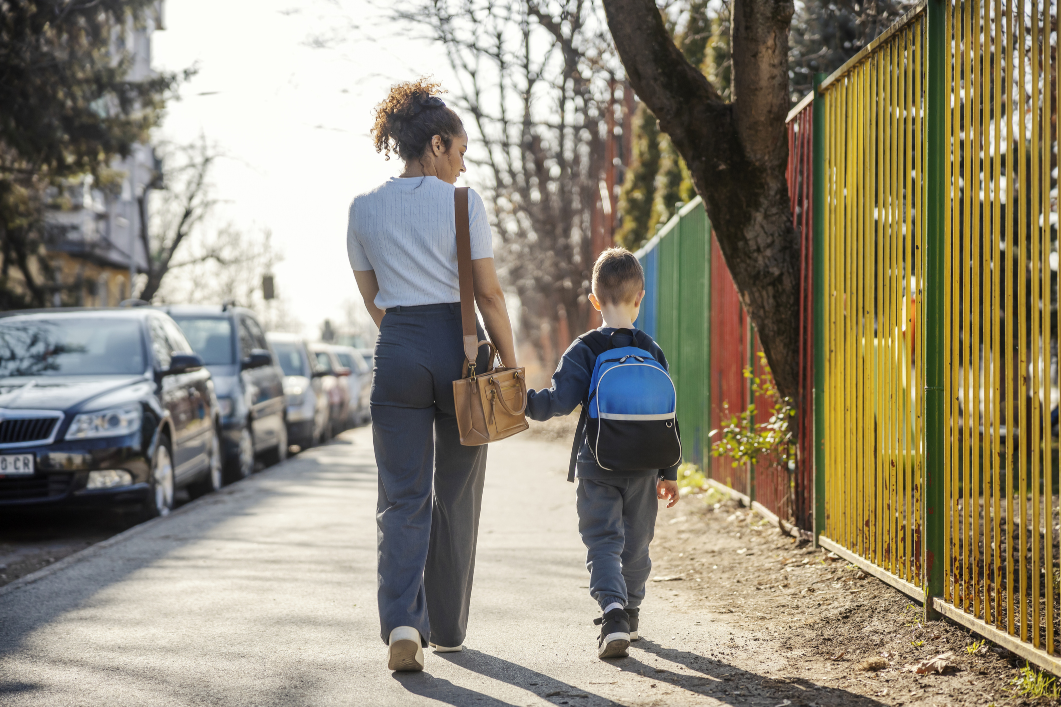 Rear view of mother taking child to school