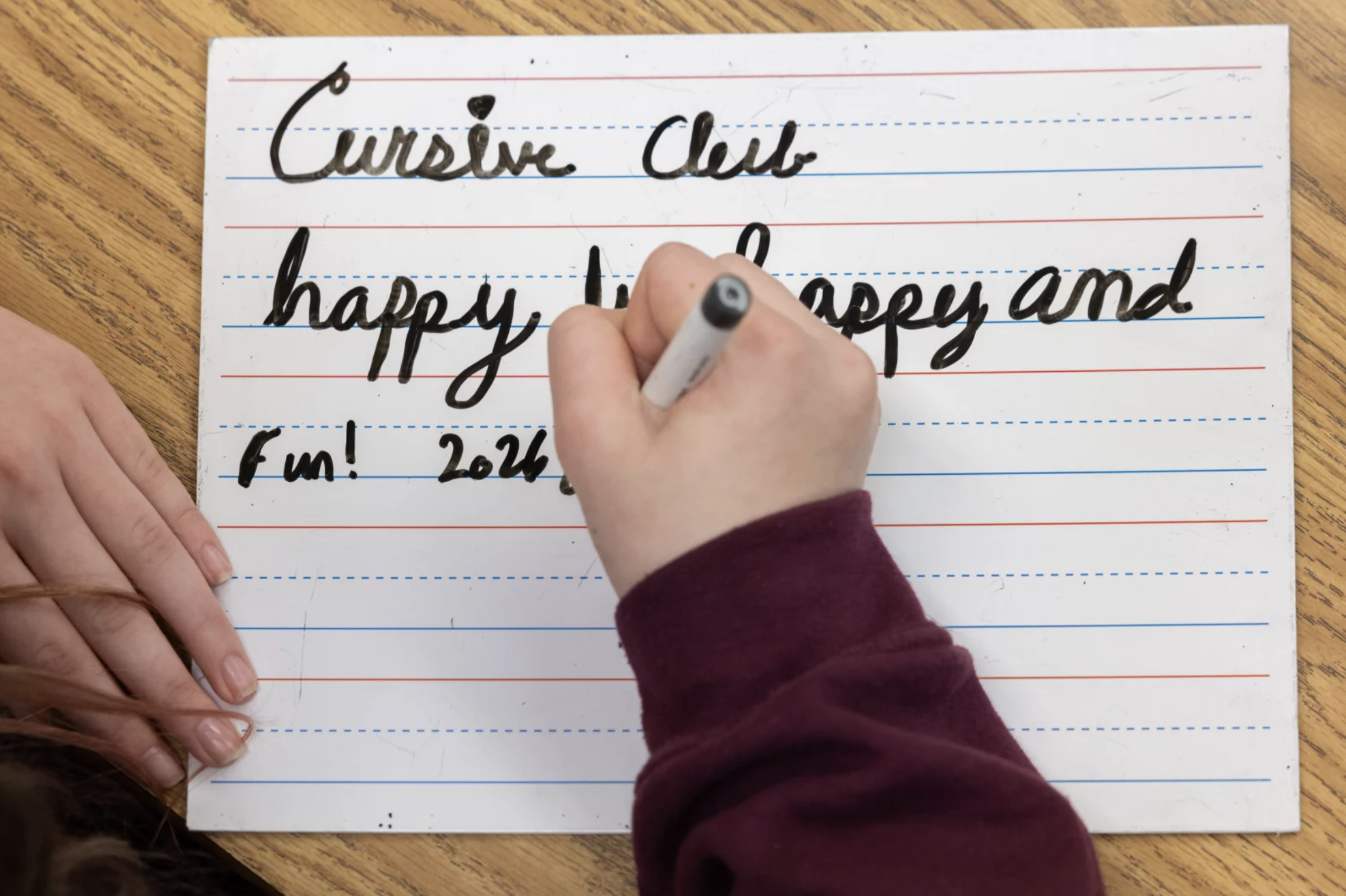 Child writes in cursive on lined paper
