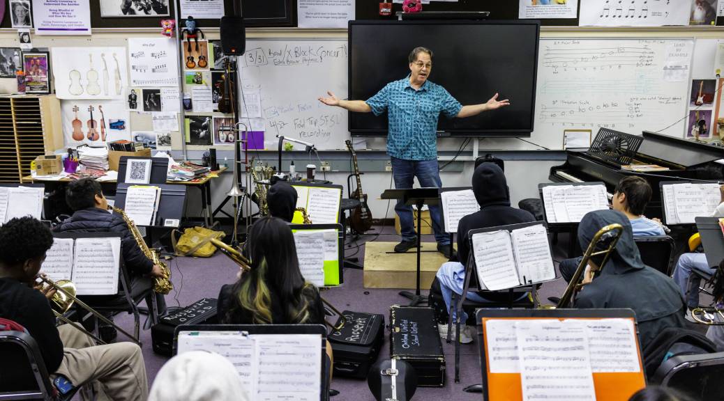 Man stands in front of students in band class.