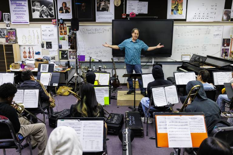 Man stands in front of students in band class.