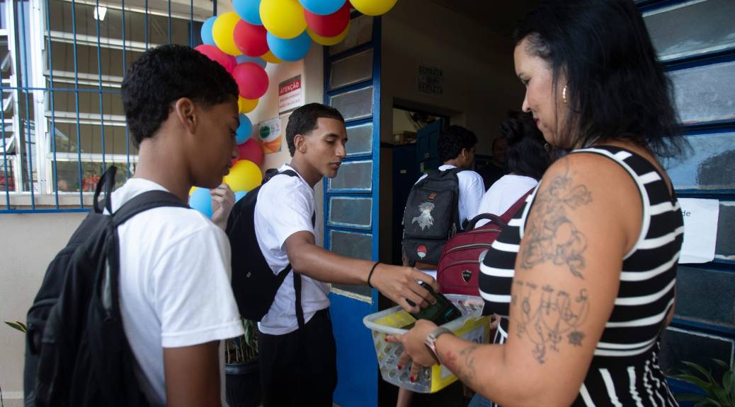 Teacher collects cell phones from students at school.