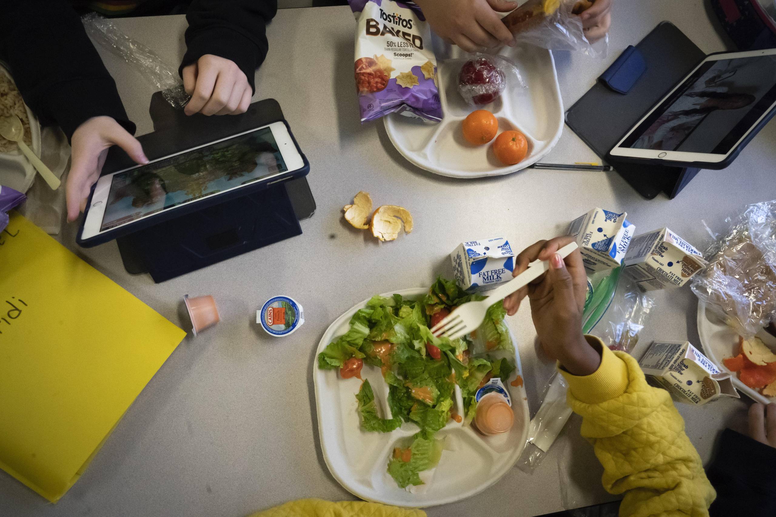 Photographed from above, seventh-graders sit together at a cafeteria table during lunch.