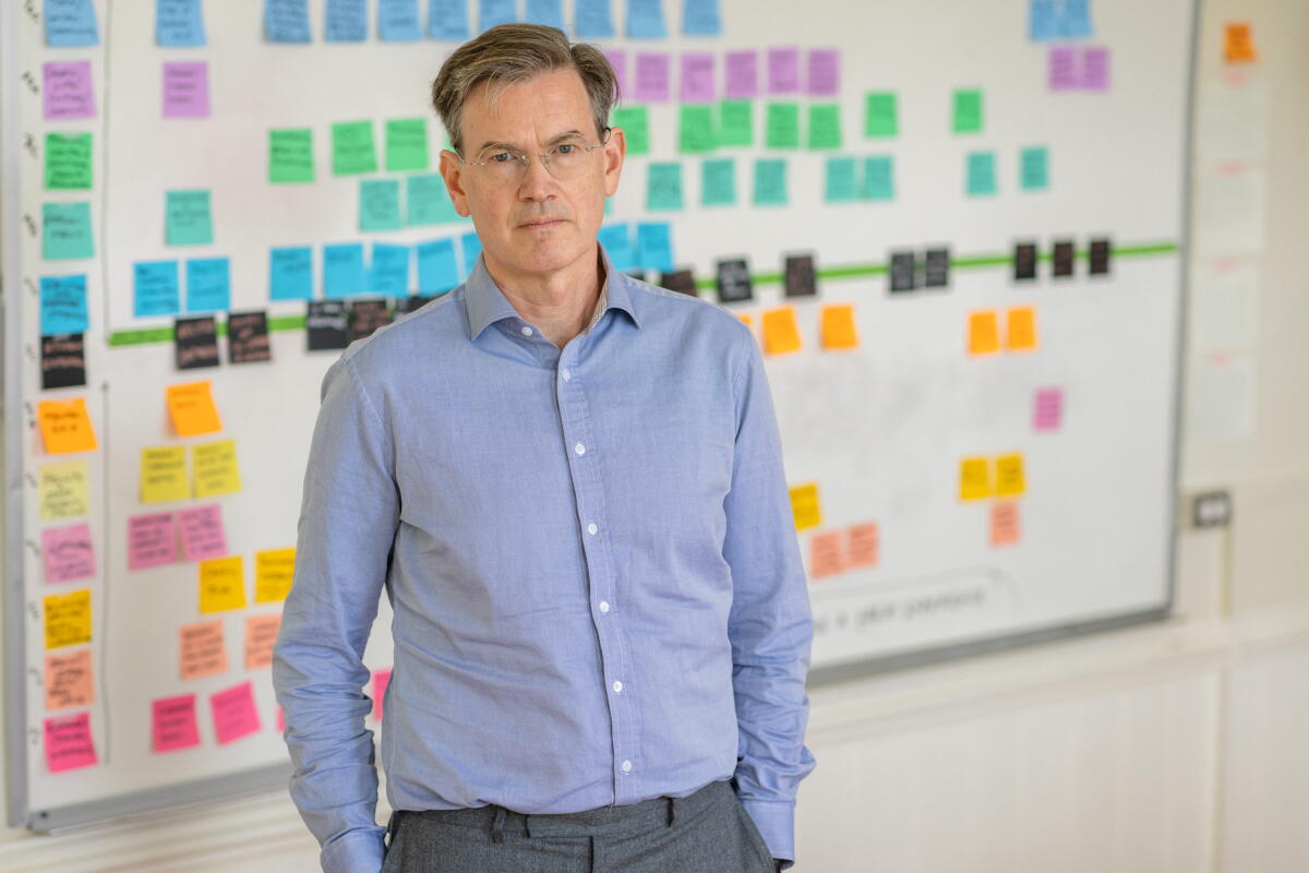 Man stands in front of whiteboard plastered with sticky notes.