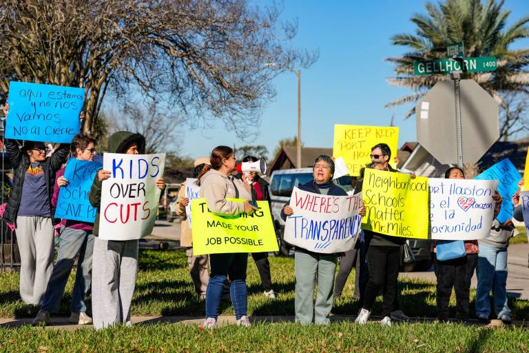 Parents gather on grass holding signs of protest
