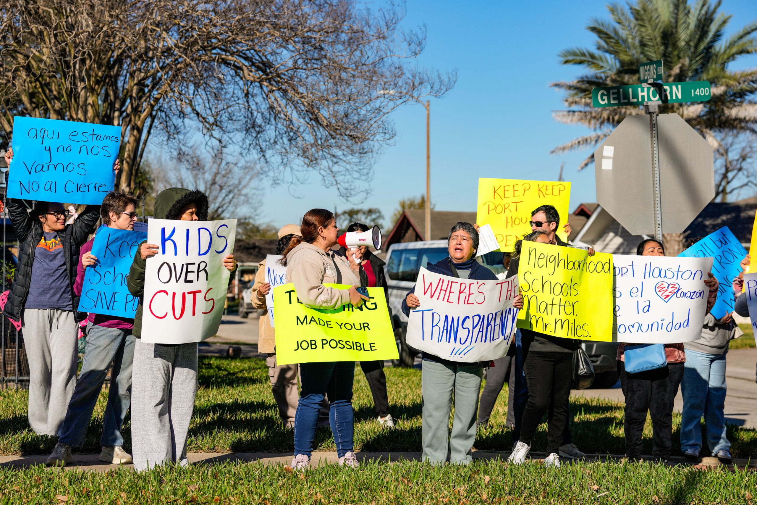 Parents gather on grass holding signs of protest