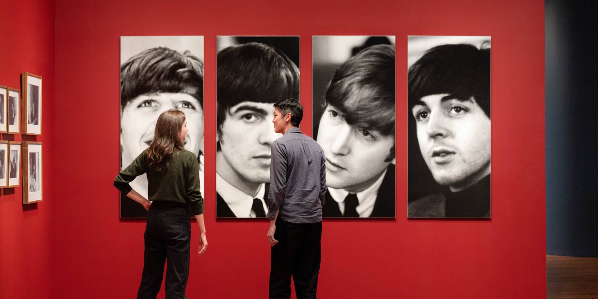 Two people view photographs of The Beatles from the Paul McCartney exhibit