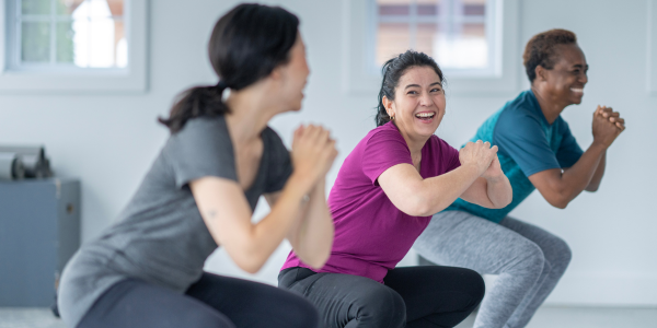 Three people doing squats with the first two front people looking at each other