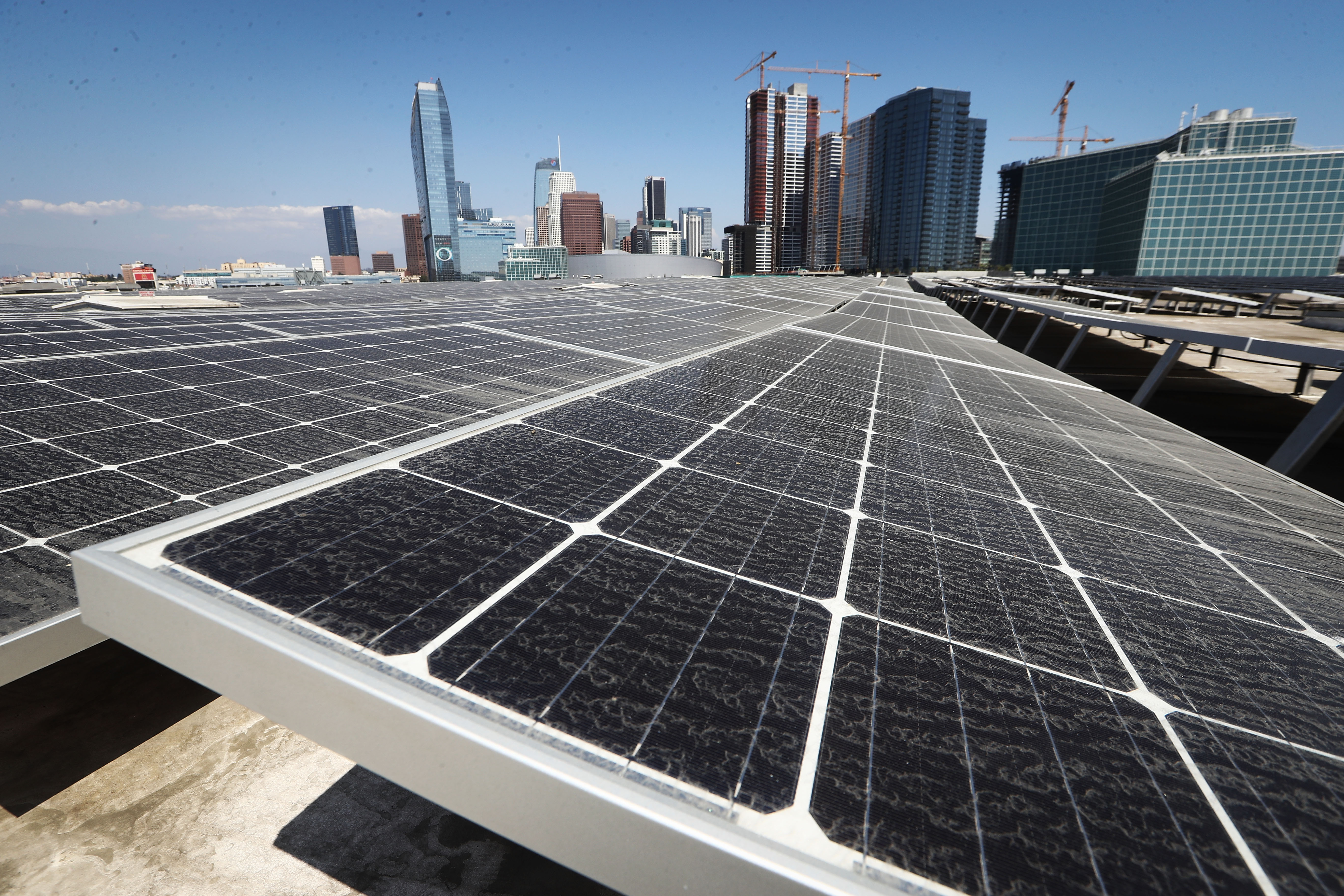 A large solar panel array, with a city skyline in the background.