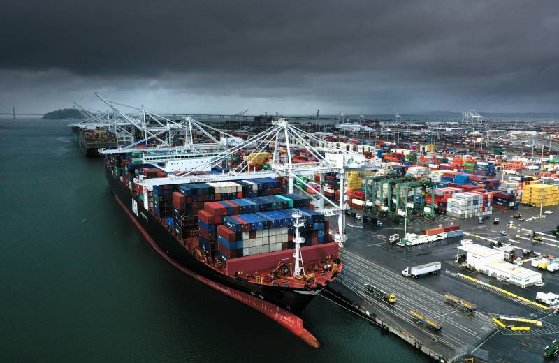An aerial view of a very large container ship docked at a port.