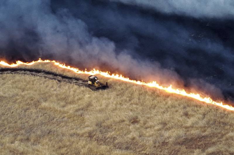 A bulldozer moves near a wildfire.